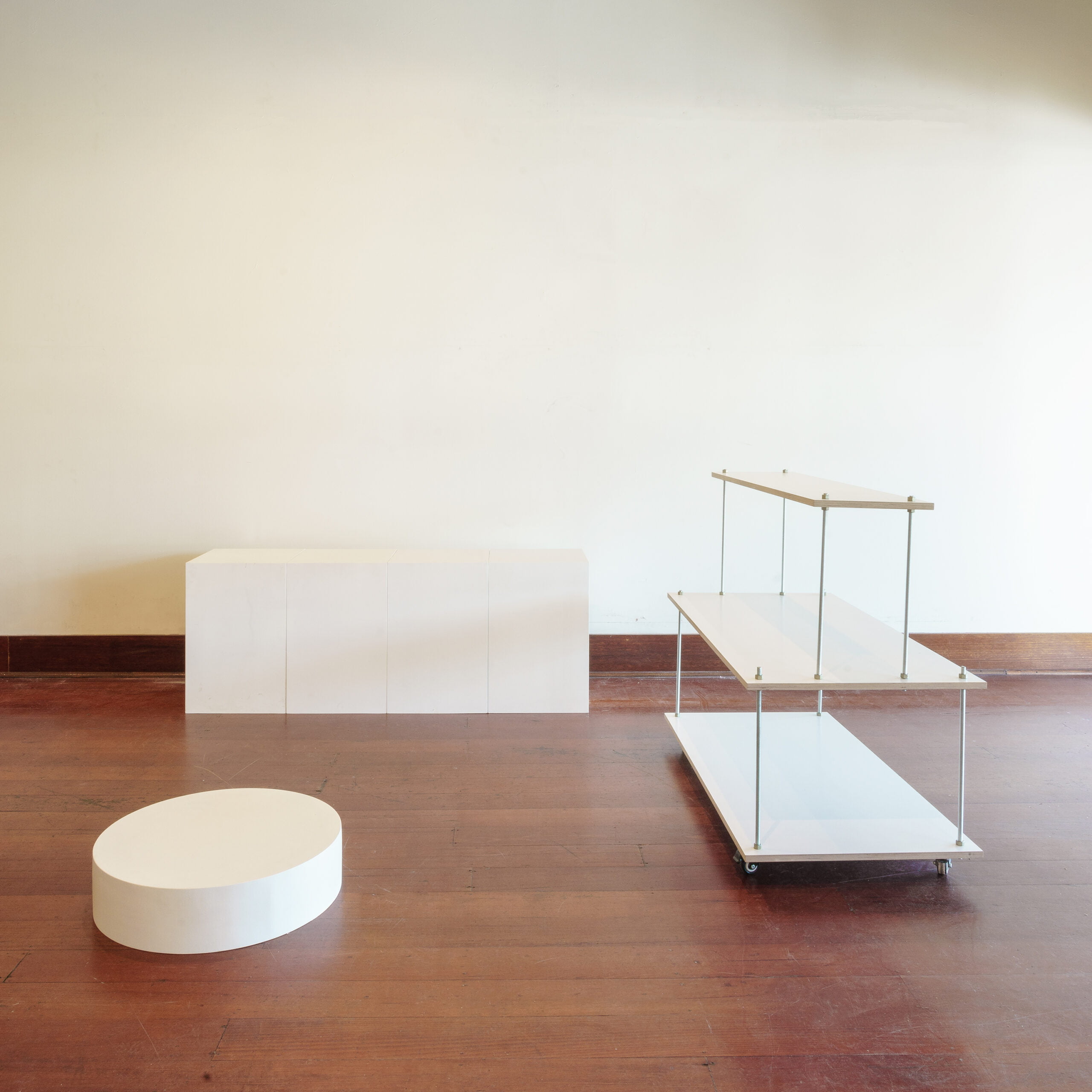 four white plinths, one white centered floating stand and one round platform plinth