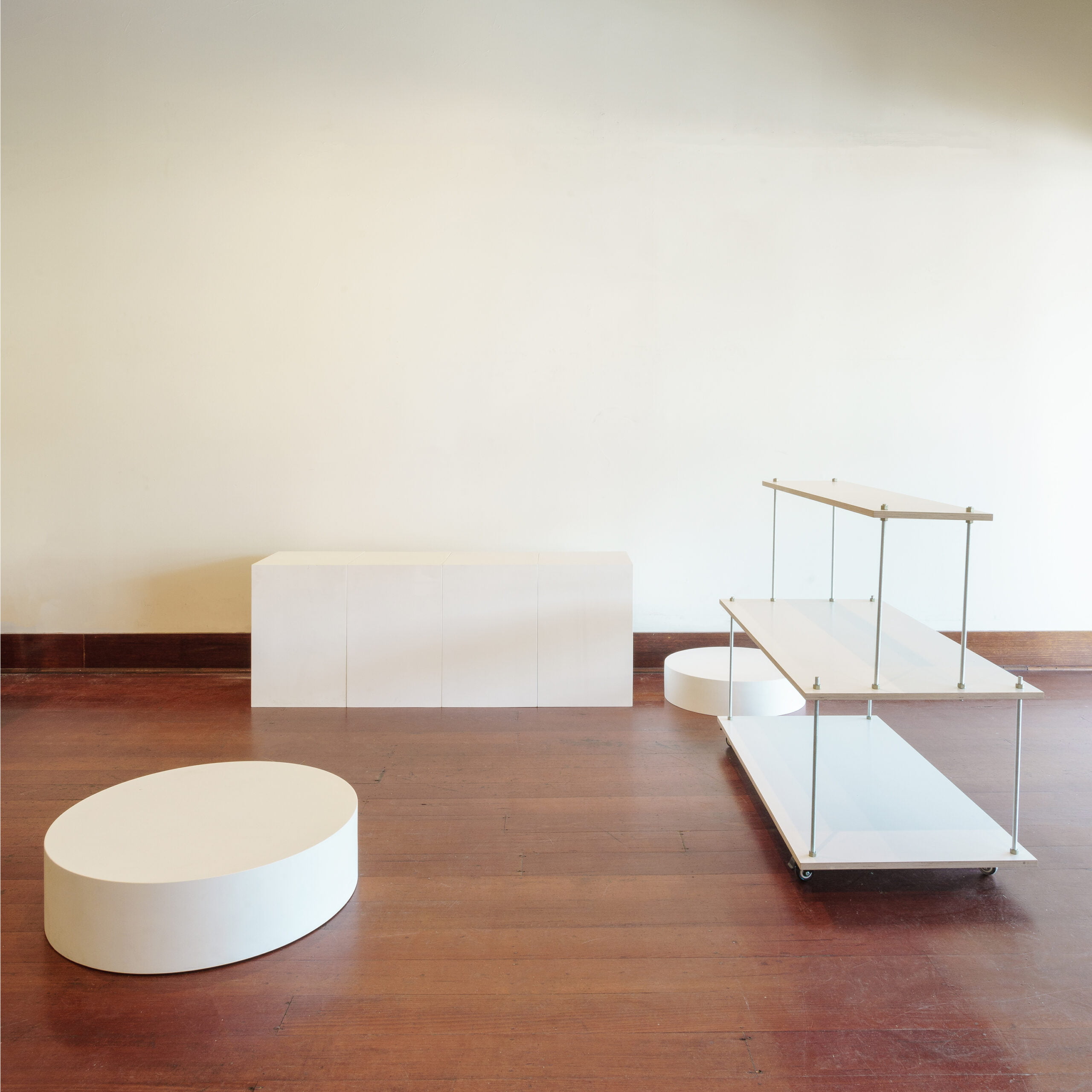 four white plinths, one white centered floating stand and two round platform risers